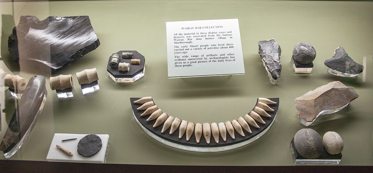 Stone tools and pendant-like objects arranged in a museum display case.