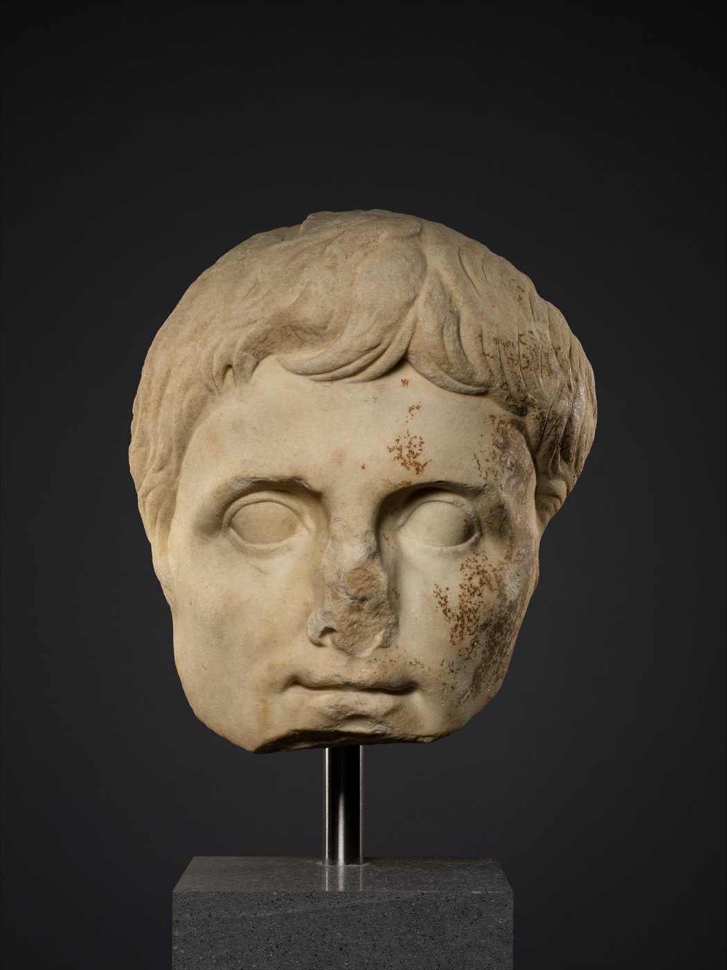 A marble male head with short, carefully arranged curls.