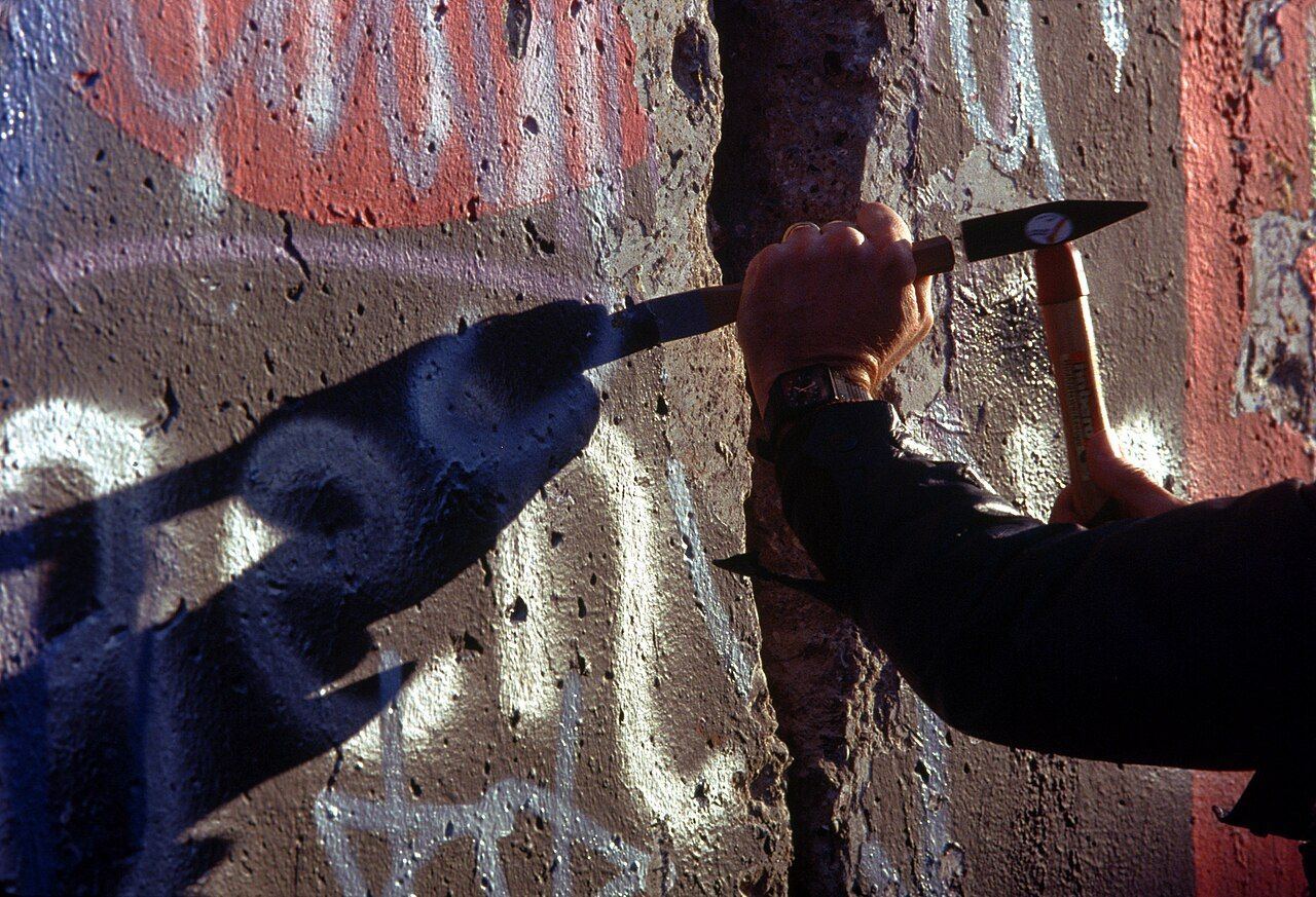 Chipping a souvenir from the Berlin Wall
