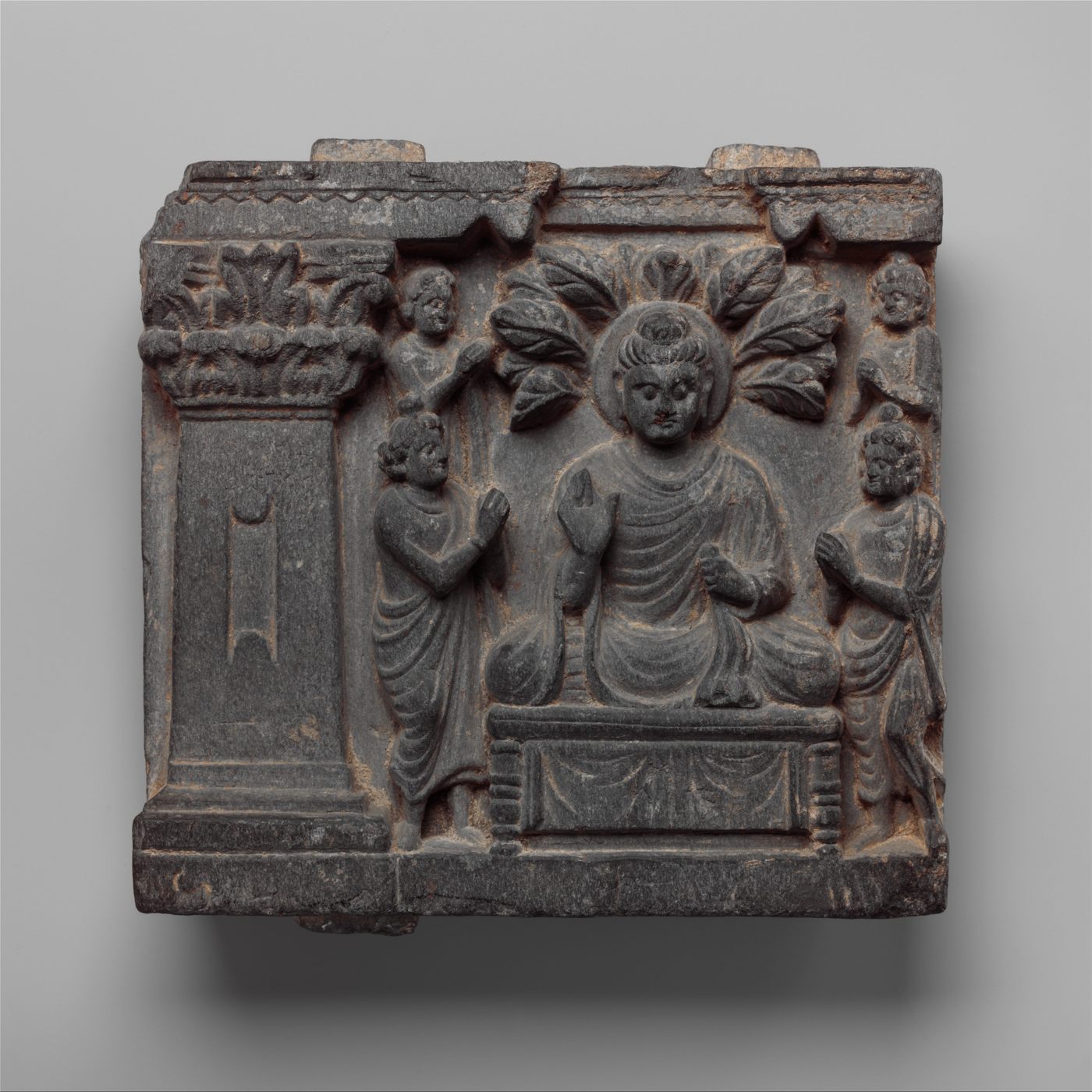 A stone relief depicting the Buddha with worshippers.