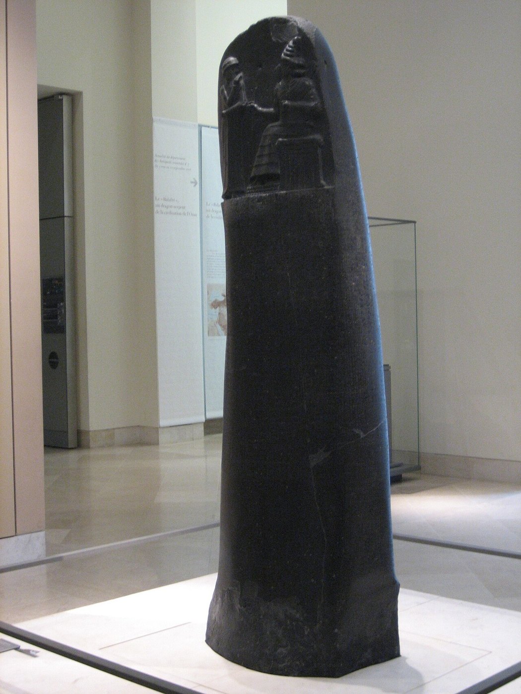 A dark stone stele with a carved scene and lines of cuneiform.