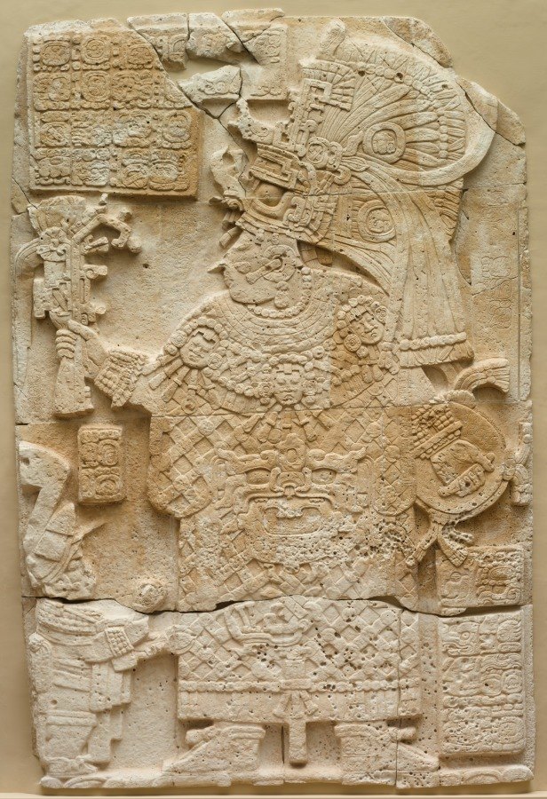 A carved limestone ruler in elaborate dress, surrounded by glyphs.