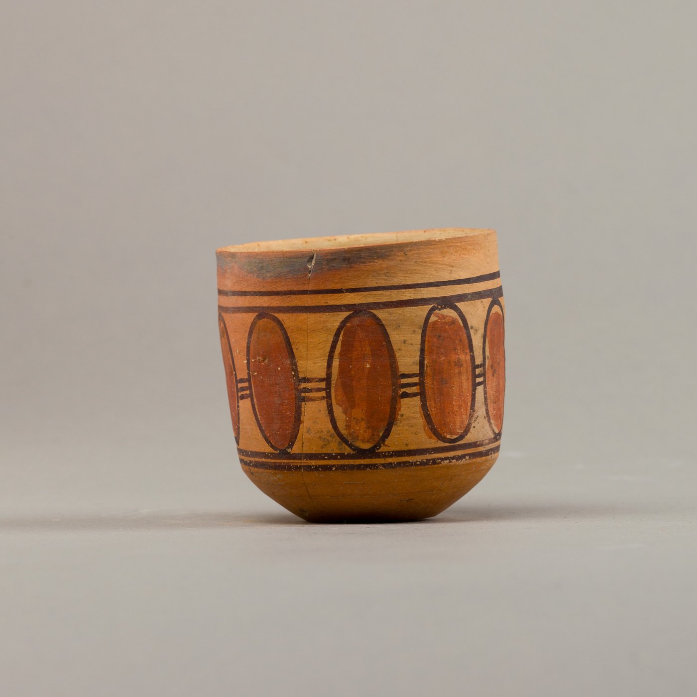 A cup decorated with dark geometric patterns on a light surface.