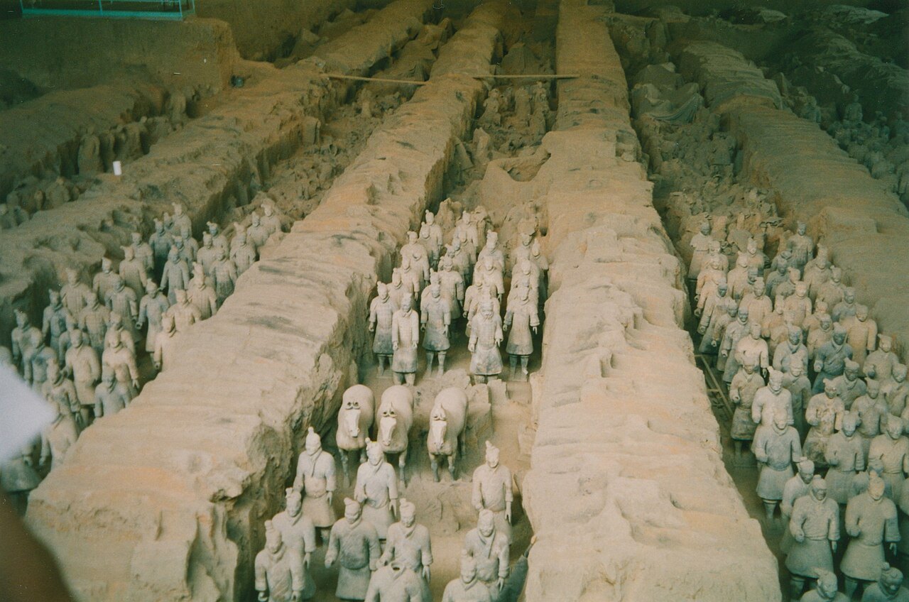 Rows of excavated terracotta warriors inside a sheltered pit.