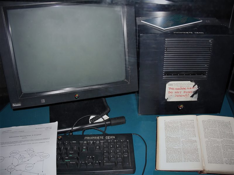 Monitor, estación NeXT negra y documento de la propuesta sobre una mesa de exposición