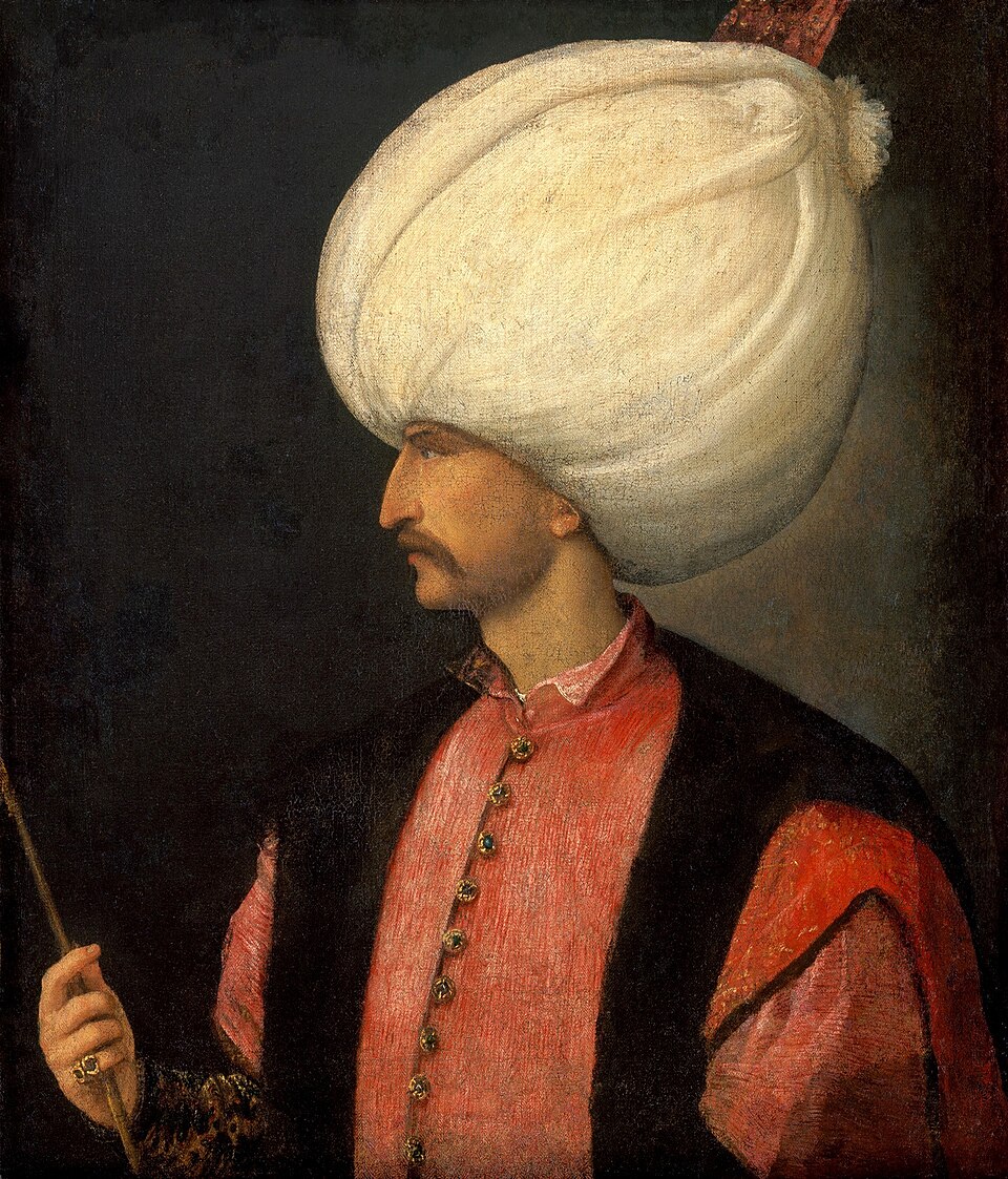 Solimán de perfil con un gran turbante blanco y ropa roja.